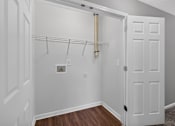 Thumbnail 13 of 18 - A white closet with a wooden floor and a white door.
