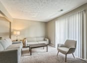 Thumbnail 3 of 20 - A living room with a grey couch, a white chair, and a grey armchair.