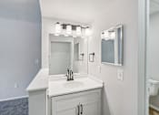 Thumbnail 9 of 31 - A bathroom with a sink, mirror, and lighting fixture.