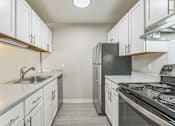 Thumbnail 1 of 30 - A kitchen with white cabinets and a black refrigerator.