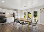 Thumbnail 15 of 26 - A modern kitchen with a dining table and chairs.