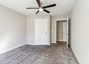 Thumbnail 14 of 32 - A room with a ceiling fan and carpeted floor.