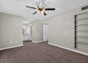 Thumbnail 5 of 30 - A room with a ceiling fan and a carpeted floor.