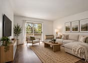 Thumbnail 7 of 35 - A living room with a couch, chair, and a table with a plant on it.