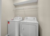 Thumbnail 13 of 27 - Two white front-loading washing machines in a laundry room at Arbours at Victoria Place in Prattville, AL