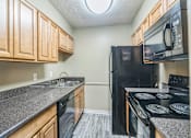 Thumbnail 4 of 20 - A kitchen with black appliances and wooden cabinets.