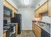 Thumbnail 9 of 20 - A kitchen with black appliances and wooden cabinets.