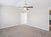Thumbnail 14 of 25 - A room with a ceiling fan and carpeted floor.