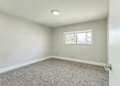 Thumbnail 10 of 30 - A room with a carpeted floor and a window.