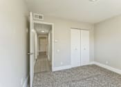 Thumbnail 9 of 30 - A long hallway with a carpeted floor and white walls.