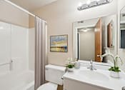 Thumbnail 17 of 31 - A bathroom with a white toilet, sink, and a painting on the wall.
