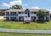 Thumbnail 13 of 23 - Two-story apartment with white fence at Arbours at Victoria Place Prattville AL
