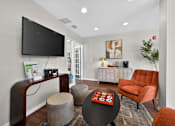 Thumbnail 24 of 32 - Community room at Renaissance at Carol Stream featuring a television, chair, table, and plant in Carol Stream, IL.
