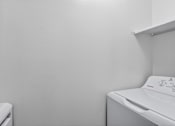 Thumbnail 12 of 24 - A white washing machine in a laundry room.