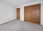 Thumbnail 10 of 34 - A room with a carpeted floor and two brown doors.