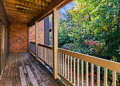 Thumbnail 14 of 34 - A wooden deck with a railing and a view of a forest.