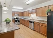 Thumbnail 11 of 34 - A kitchen with wooden cabinets and a black refrigerator.