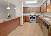 Thumbnail 12 of 34 - A kitchen with wooden cabinets and a granite countertop.