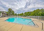 Thumbnail 24 of 31 - A large swimming pool surrounded by a metal fence and trees.