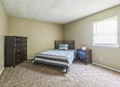 Thumbnail 8 of 20 - A bedroom with a bed, nightstand, and dresser.