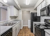 Thumbnail 1 of 25 - Kitchen with white cabinets and black appliances at Park at Meadow Ridge Montgomery AL