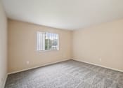Thumbnail 16 of 31 - A room with a carpeted floor and a window with blinds.
