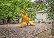 Thumbnail 26 of 31 - A playground with a yellow slide and a red climbing frame.