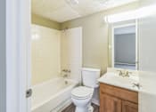 Thumbnail 12 of 20 - A white toilet sits next to a bathtub in a bathroom.