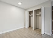 Thumbnail 9 of 26 - A room with a white wall and a brown floor with a white door.
