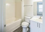 Thumbnail 7 of 16 - A white bathroom with a toilet, sink, and bathtub.