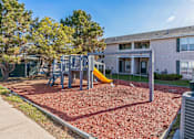 Thumbnail 15 of 16 - A playground with a slide and swings in front of a building.