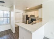 Thumbnail 1 of 16 - A kitchen with white countertops and a window with blinds.