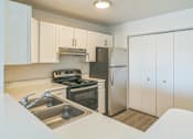 Thumbnail 2 of 16 - A kitchen with a stove, sink, and refrigerator.