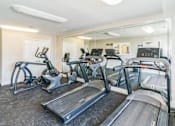 Thumbnail 11 of 16 - A gym with treadmills and elliptical machines.