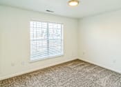 Thumbnail 10 of 16 - A room with a carpeted floor and a window with blinds.