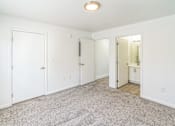 Thumbnail 8 of 16 - A white room with a carpeted floor and a door on the left.