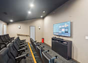 Thumbnail 16 of 20 - A row of black chairs are arranged in front of a television in a room.