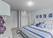 Thumbnail 3 of 39 - a bedroom with a bed and white walls and blue and white bedding