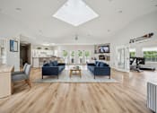 Thumbnail 20 of 31 - A spacious living room with a skylight and hardwood floors.
