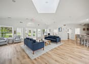 Thumbnail 23 of 31 - A spacious living room with a blue sofa and wooden flooring.