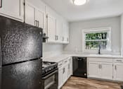 Thumbnail 3 of 27 - A black refrigerator in a kitchen with white cabinets and a window.