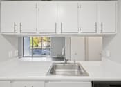 Thumbnail 5 of 26 - A kitchen with white cabinets and a stainless steel sink.