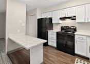 Thumbnail 2 of 34 - A kitchen with black appliances and white cabinets.