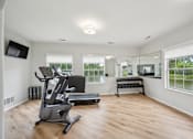 Thumbnail 21 of 31 - A spacious room with a treadmill and a television.
