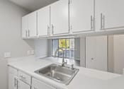 Thumbnail 3 of 26 - A kitchen with white cabinets and a stainless steel sink.
