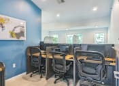 Thumbnail 17 of 20 - A room with blue walls and four black chairs with desks in front of them.