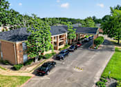 Thumbnail 29 of 30 - A black car is parked in a parking lot in front of a building.