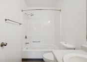 Thumbnail 10 of 26 - A white bathroom with a toilet, sink, and bathtub.