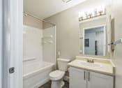 Thumbnail 16 of 30 - A white bathroom with a toilet, sink, and bathtub.