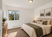 Thumbnail 12 of 35 - A bedroom with a large bed and a window overlooking trees.